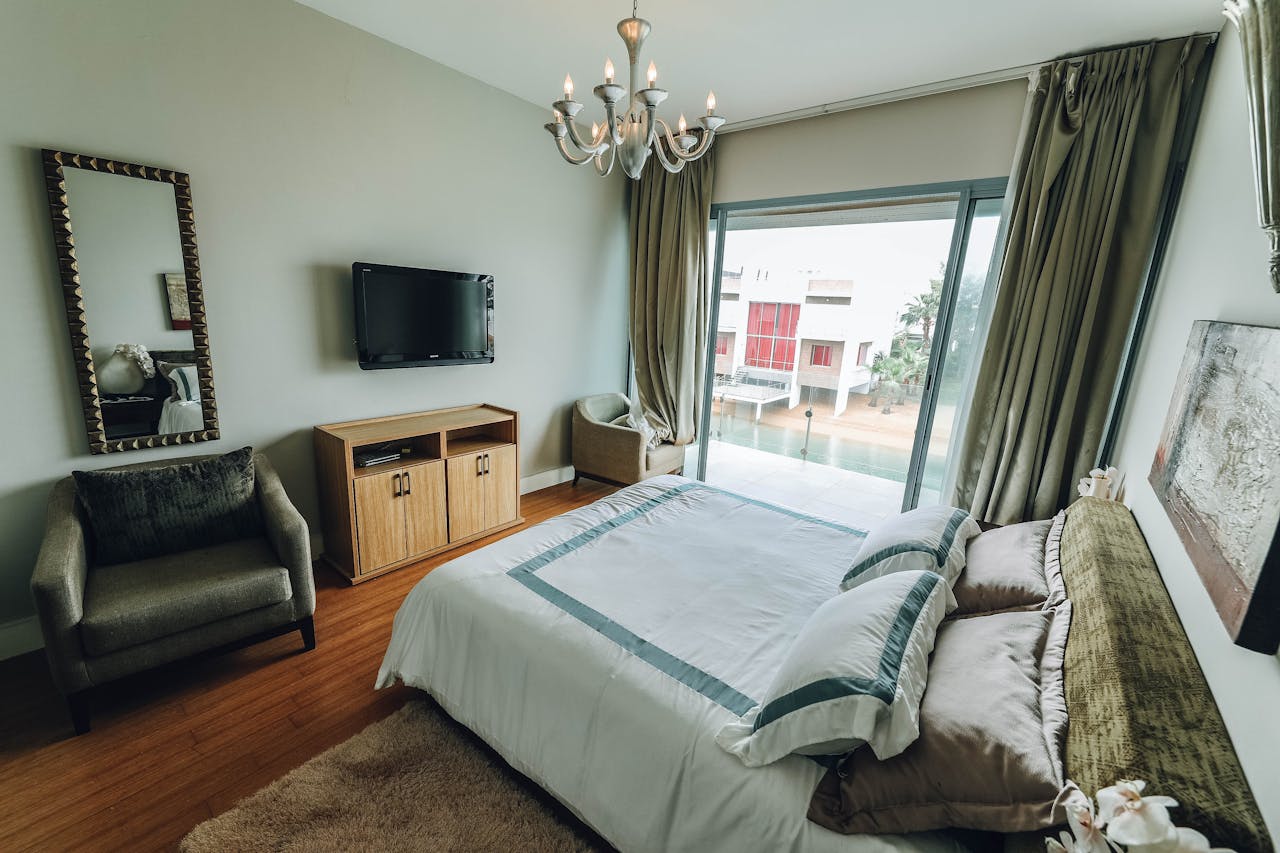 Stylish contemporary bedroom featuring modern furniture, a chandelier, and natural lighting through sliding doors.