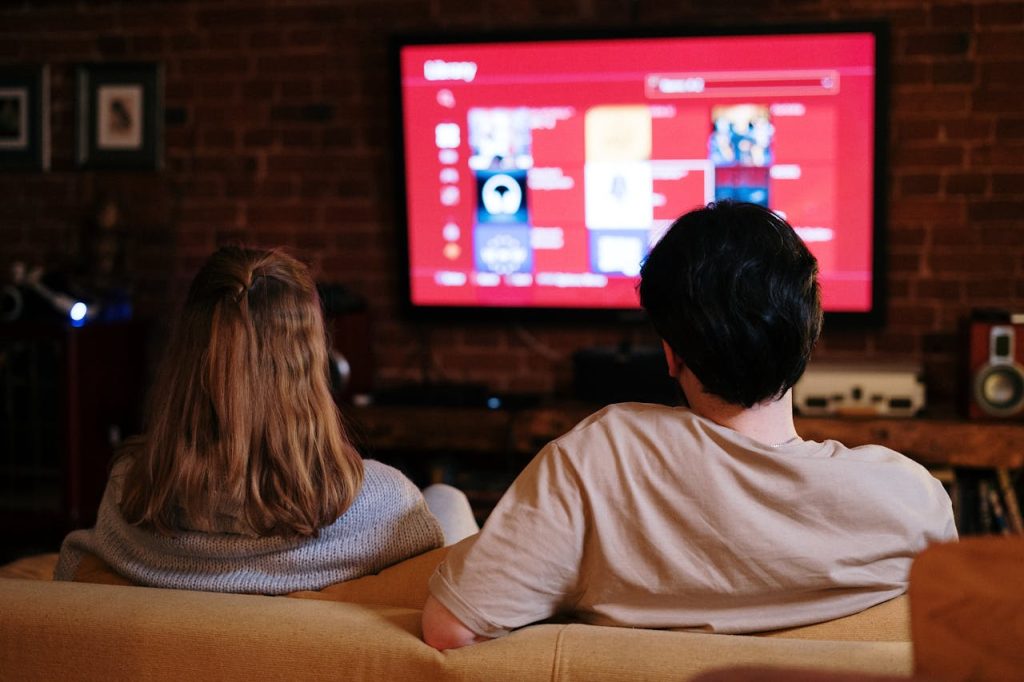 pexels-photo-4009409 A couple enjoys streaming shows on a large TV in a cozy, brick-walled living room.